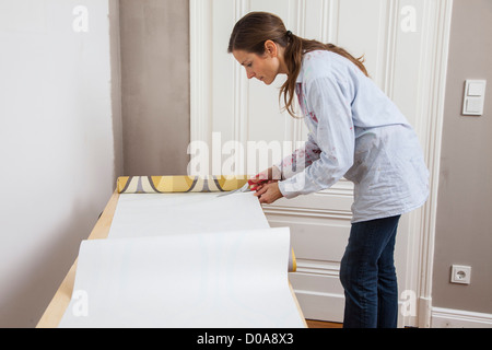 Junge Frau ist ihr Haus renovieren. Tapezieren, neue Tapete. Zum Selbermachen. Stockfoto