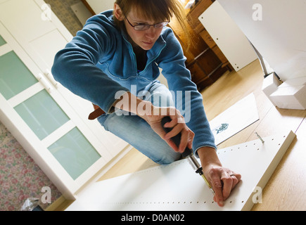 DIY. Low-Winkel einer Frau Montage IKEA Flachgehäuse Möbel. Stockfoto