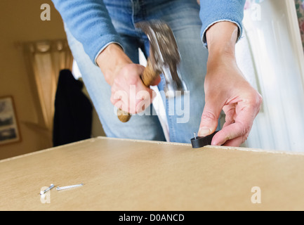 DIY. Eine Frau, einen Nagel ins Holz zu hämmern. Stockfoto