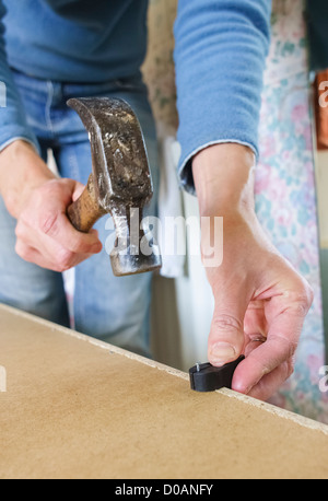 DIY. Eine Frau, einen Nagel ins Holz zu schlagen. Stockfoto