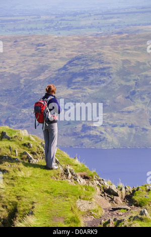 Eine weibliche Wanderer hält am langen Stil, nach Ansicht des Haweswater in der Ferne im Lake District zu nehmen. Stockfoto