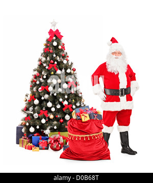 In voller Länge Portrait von Weihnachtsmann stehend nahe bei einem Weihnachtsbaum isoliert auf weißem Hintergrund Stockfoto