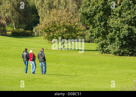 Drei Menschen, die zu Fuß über öffnen Rasen gegenüber einigen Bäumen an einem sonnigen Tag im Chartwell House in Kent. Stockfoto