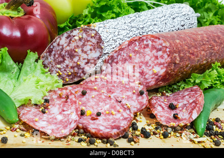 Stillleben mit in Scheiben geschnittenen rumänischen Salami und Gemüse Stockfoto