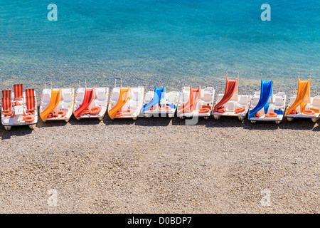 Bunten Tretbooten an einem steinigen Strand Stockfoto