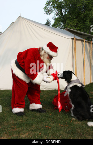 Santa Claus präsentiert einen Knochen als Geschenk mit einem Hund in einer alten West-Szene Stockfoto