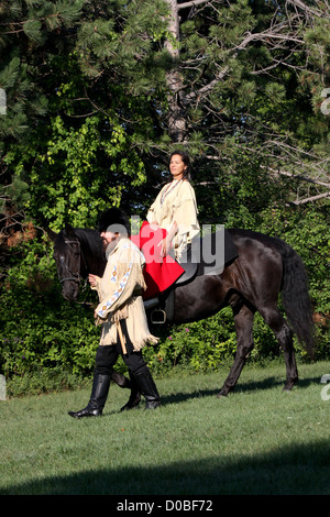 Eine Native American Indian Frau auf einem schwarzen Pferd mit einem Pionier Stockfoto