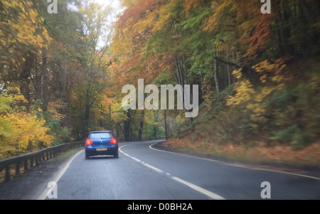 Brechen Sie die Lichter eines Wagens vor Annäherung an eine Kurve auf nasser Fahrbahn. Stockfoto