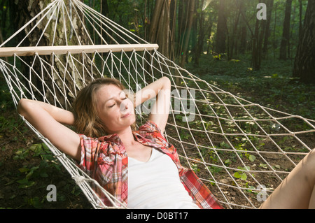 Schöne Frau in Hängematte draußen im Wald entspannen Stockfoto