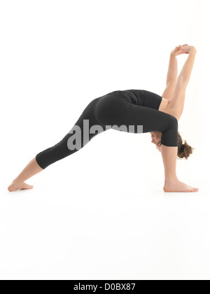 Seitenansicht der jungen Frau zeigen schwierige Yoga-Pose, gekleidet in schwarz auf weißem Hintergrund, Stockfoto