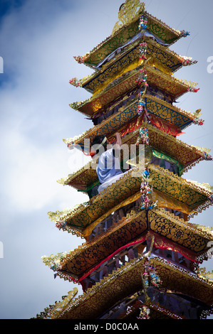 Eine Person klettert auf den Turm, wo der verstorbene König von Ubud wartet auf die Feuerbestattung mit der Angebote getroffen werden Stockfoto