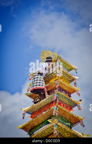 Eine Person klettert auf den Turm, wo der verstorbene König von Ubud wartet auf die Feuerbestattung mit der Angebote getroffen werden Stockfoto