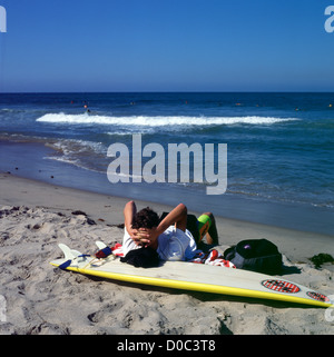 Junger Mann ruht auf einem Surf board beobachten Surfer im Ozean in Malibu Beach, Kalifornien, USA KATHY DEWITT Stockfoto