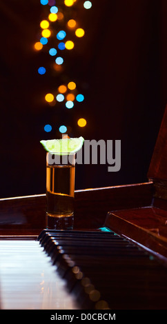 Dankbarkeit für den Maestro, Glas mit Tequila auf einem Klavier. Stockfoto