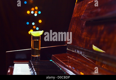 Dankbarkeit für den Maestro, Glas mit Tequila auf einem Klavier. Stockfoto