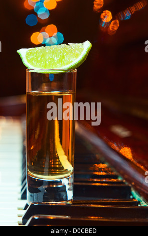 Dankbarkeit für den Maestro, Glas mit Tequila auf einem Klavier. Stockfoto