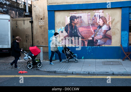 Hackney 18. November 2012. Ecke von Andrews Road und Mare Street. Peeling-Foto auf Café Mauer und zwei Personen mit Kinderwagen Stockfoto