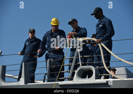 Matrosen an Bord der Arleigh-Burke-Klasse geführte Flugkörper Zerstörer USS John S. McCain (DDG-56) binden eine Messenger-Linie um eine Befestigungsleine, wie das Schiff zur Flotte Aktivitäten, Yokosuka zurück. John S. McCain ist zugeordnet, Zerstörer Geschwader (DESRON) 15 und forwa Stockfoto