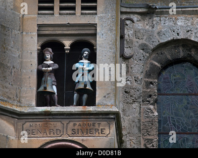 An einer Wand der Stiftskirche Notre-Dame in der Normandie Stadt Auffay sind angehängte zwei hölzerne Glöckner. Stockfoto