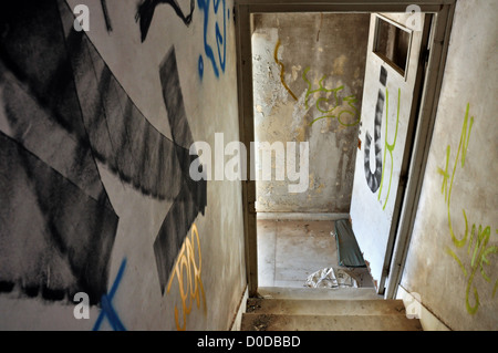 Malte Pfeil auf der Treppe unter Hinweis auf die Tür in einem verlassenen Haus zu verlassen. Stockfoto