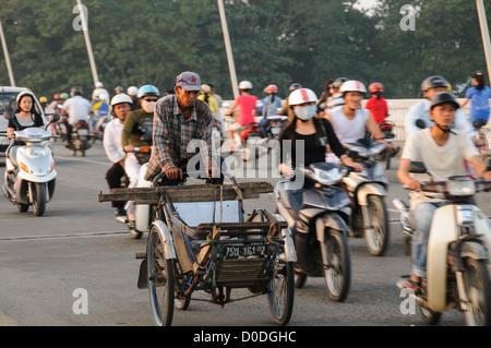 HUE, Vietnam - ein Mann fährt eine alte Rikscha Fahrrad durch Feierabendverkehr auf Cau Phu Xuan in Hue, Vietnam. Stockfoto