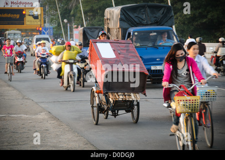 Ein Mann auf einem modifizierten Fahrrad transportiert eine Kommode in Cau Phu Xuan im Abend Verkehr in Hue, Vietnam. Stockfoto