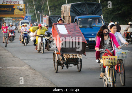HUE, Vietnam - ein Mann auf einer modifizierten Fahrrad transportiert eine Kommode über Cau Phu Xuan im Feierabendverkehr in Hue, Vietnam. Stockfoto