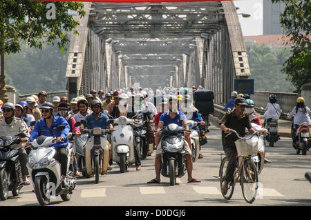 Hunderte von Roller und Fahrräder überqueren Cau Truong Tien im Verkehr in Hue, Vietnam. Stockfoto