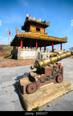 HUE, Vietnam – Eine restaurierte Pagode und Kanone in der Kaiserstadt in Hue, Vietnam. Der Komplex ist ein selbstgeschlossener und befestigter Palast und umfasst die lila Verbotene Stadt, die das innere Heiligtum des kaiserlichen Haushalts war, sowie Tempel, Höfe, Gärten und andere Gebäude. Ein großer Teil der Kaiserlichen Stadt wurde während des Vietnamkrieges beschädigt oder zerstört. Sie ist heute zum UNESCO-Weltkulturerbe ernannt. Stockfoto