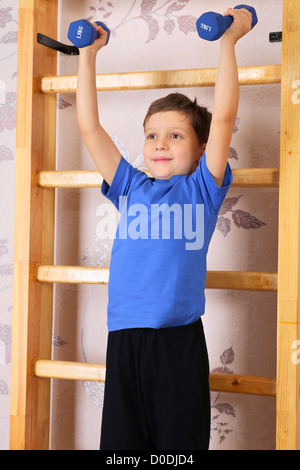 Der junge im Vorschulalter hebt die Hanteln in der heimischen Sporthalle Stockfoto