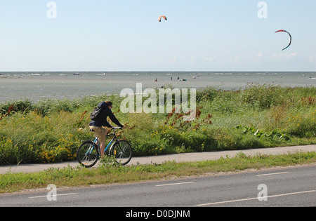 Mann mit dem Fahrrad mit Kite-Surfer am Meer im Hintergrund Stockfoto