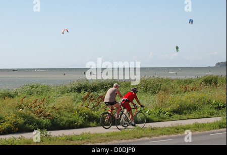 Leute mit dem Fahrrad mit Kite-Surfer am Meer im Hintergrund Stockfoto