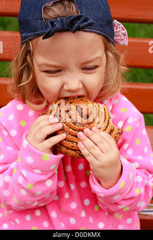 Das kleine Mädchen beißt ein leckeres Brot Stockfoto