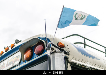 Guatemala Flagge auf einem Huhn Buse hinter dem Mercado Municipal (Stadtmarkt) in Antigua, Guatemala. Aus diesem umfangreichen zentralen Busbahnhof strahlenförmig der Routen in Guatemala. Oft bunt bemalt, die Huhn-Busse sind nachgerüsteten amerikanische Schulbusse und bieten ein günstiges Transportmittel im ganzen Land. Stockfoto