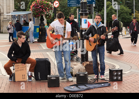 Typische Straßenszene mit drei irischen Musikern Gitarre Straßenmusik im Stadtzentrum auf der Grafton Street Dublin Irland Irland Stockfoto