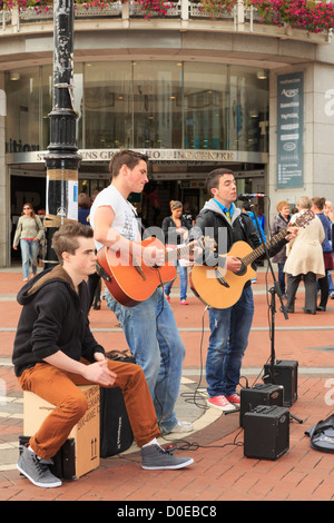 Typische Street-Szene mit drei irischen Musikern junge Männer, die in der Innenstadt an der Grafton Street Dublin Irland Gitarre spielen Stockfoto