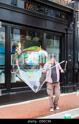 Irische Straße Entertainer macht eine große Blase, die mit zwei Stöcken im Stadtzentrum auf der Grafton Street, Dublin, Südirland, Eire Stockfoto