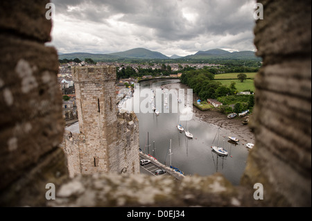 CAERNARFON, Wales – Blick auf den Fluss und die Boote von einem Turm auf Caernarfon Castle im Nordwesten von Wales. Ursprünglich stand an der Stelle eine Burg aus dem späten 11. Jahrhundert, aber im späten 13. Jahrhundert ließ König Eduard I. ein neues Gebäude in Auftrag geben, das bis heute besteht. Es hat markante Türme und ist eines der am besten erhaltenen Burgen der Reihe, die Edward I. in Auftrag gab. Stockfoto