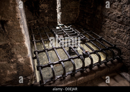 CAERNARFON, Wales — Ein schwarzer Metallgrill bedeckt den ursprünglichen Wasserbrunnen von Caernarfon Castle im Nordwesten von Wales. Ursprünglich stand an der Stelle eine Burg aus dem späten 11. Jahrhundert, aber im späten 13. Jahrhundert ließ König Eduard I. ein neues Gebäude in Auftrag geben, das bis heute besteht. Es hat markante Türme und ist eines der am besten erhaltenen Burgen der Reihe, die Edward I. in Auftrag gab. Stockfoto