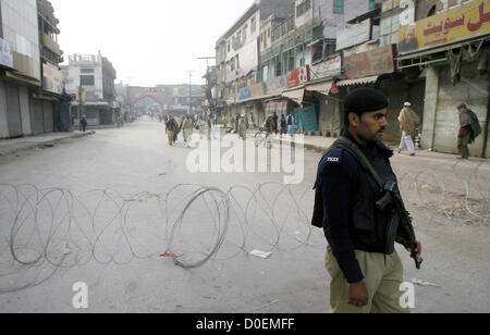 Polizeibeamte stehen Warnung, wie die Straße aus Sicherheitsgründen auf Hashtnagri Gebiet in Peshawar Freitag, 23. November 2012 geschlossen ist. In Moharram-Ul-Haram unterhält Regierung Narr Beweis Sicherheitsvorkehrungen terroristischen Aktivitäten während der Prozession im Konto des Ashora über die Pakistan vermieden. Stockfoto