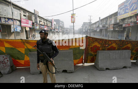 Polizeibeamte stehen Warnung, wie die Straße aus Sicherheitsgründen am Khyber Bazar in Peshawar Freitag, 23. November 2012 geschlossen ist. In Moharram-Ul-Haram unterhält Regierung Narr Beweis Sicherheitsvorkehrungen terroristischen Aktivitäten während der Prozession im Konto des Ashora über die Pakistan vermieden. Stockfoto