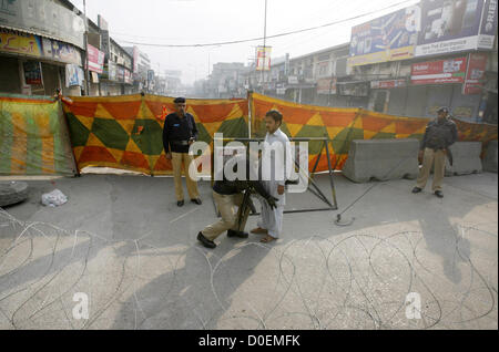 Polizeibeamte stehen wachsam und Suche Mann betrachtet die Straße geschlossen wegen Sicherheitsbedenken Khyber Bazar in Peshawar Freitag, 23. November 2012.  In Moharram-Ul-Haram unterhält Regierung Narr Beweis Sicherheitsvorkehrungen terroristischen Aktivitäten während der Prozession im Konto des Ashora über die Pakistan vermieden. Stockfoto