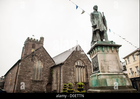 Im Vordergrund steht eine Statue des Herzogs von Wellington von der Pfarrei Kirche von St Mary es in Brecon, Wales, als Regen fällt. Stockfoto