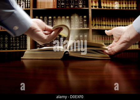 Hände halten ein altes Gesetzbuch mit Bibliothek im Hintergrund Stockfoto