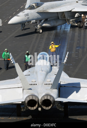 Eine Luftfahrt-Bootsmann Mate leitet eine F/A - 18C Hornet auf dem Flugdeck des Flugzeugträgers USS Nimitz 11. November 2012 im Pazifischen Ozean. Stockfoto