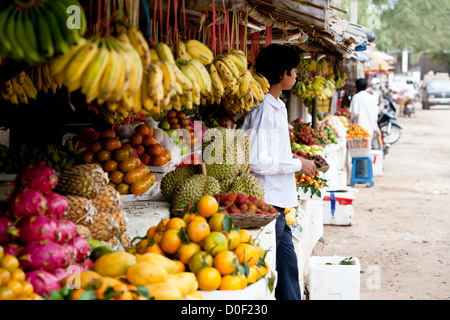 Ein junger Mann steht vor einem bunten Obstmarkt in Siem Reap, Kambodscha. Stockfoto