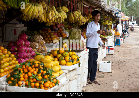 Ein junger asiatischer Mann steht vor einem bunten Obstmarkt in Siem Reap, Kambodscha. Stockfoto