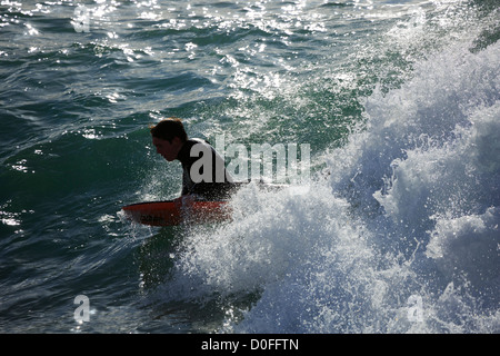 Surfer am Hafendamm, Cornwall. Eine Surfer zeigt intensiven Konzentration, wie er reitet auf eine Welle auf seinem Bodyboard liegen. Stockfoto