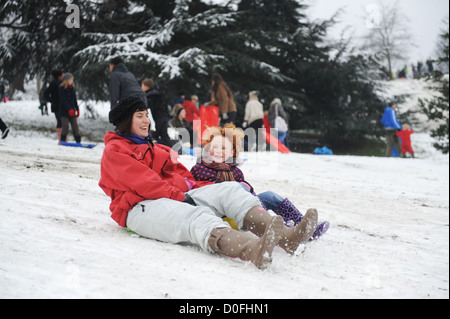 Mutter und Tochter Schlitten die Hänge in Greenwich Park, London, uk Stockfoto