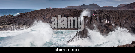 Touristen sehen Los Hervideros eine Reihe von Höhlen und Schlaglöchern auf Lanzarote, Kanarische Inseln Stockfoto